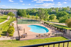 A swimming pool with a curved edge, surrounded by a fence and lounge chairs. - Caddy Corner Condo  Cozy Stay (Branson)