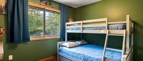 Camera con letto a castello, finestra, tende e ventilatore a soffitto.