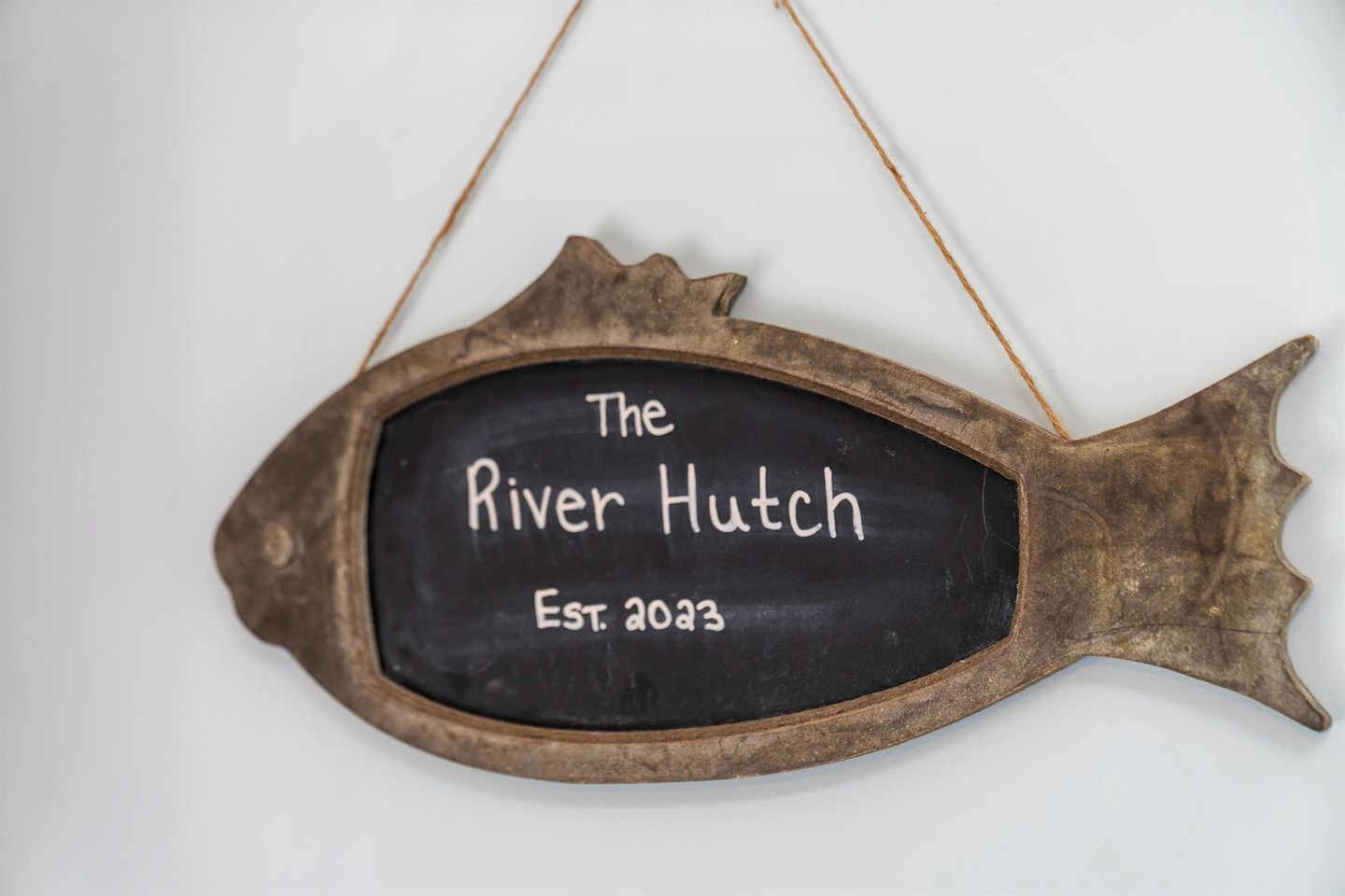 A fish-shaped chalkboard sign with 'The River Hutch' and 'Est. 2003' written on it.