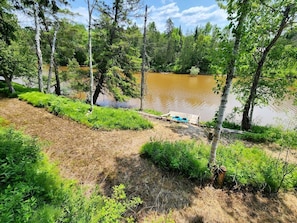 A natural landscape with a body of water, trees, and a wooden dock. - Riverfront Cabin Incredible for Outdoor Enthusiasts with Kayaks in Hessel, Michigan (Hessel)