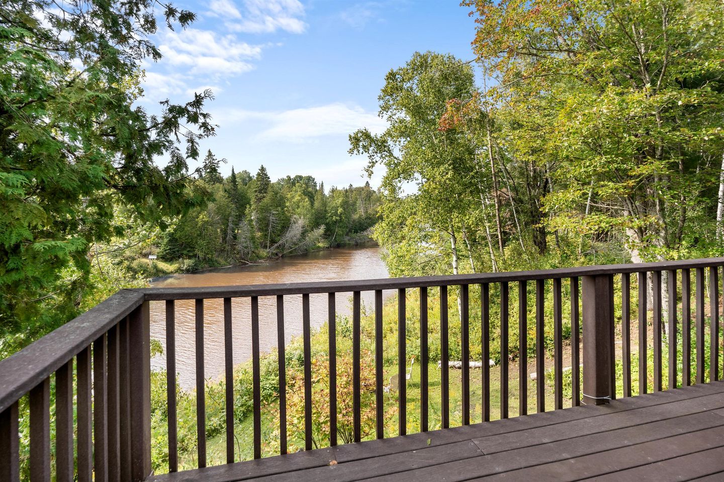 Une terrasse en bois surplombant une rivière, bordée de chaque côté par une forêt dense.