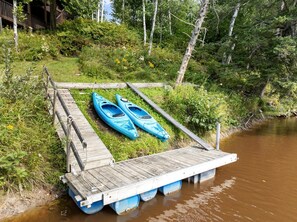 Een houten steiger die zich uitstrekt over een rivier, met twee kajaks op de steiger.