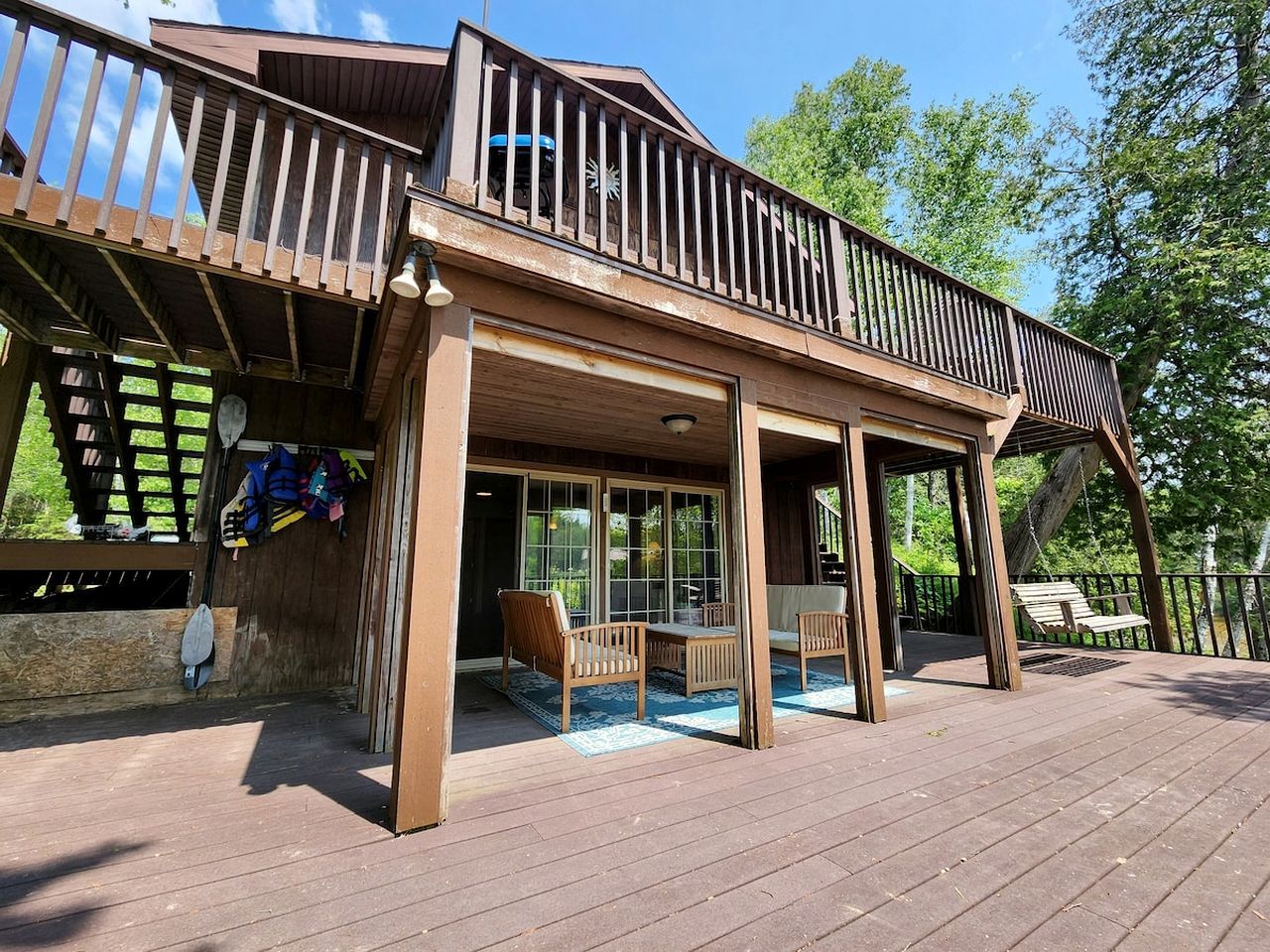 Une terrasse en bois avec un espace salon couvert et une porte de garage.