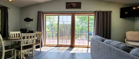 A room with a dining table and chairs, a sofa, a ceiling fan, and a large sliding glass door leading to an outdoor area.
