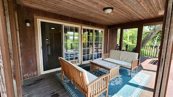 A covered outdoor seating area with a wooden bench, a sofa, and a table.