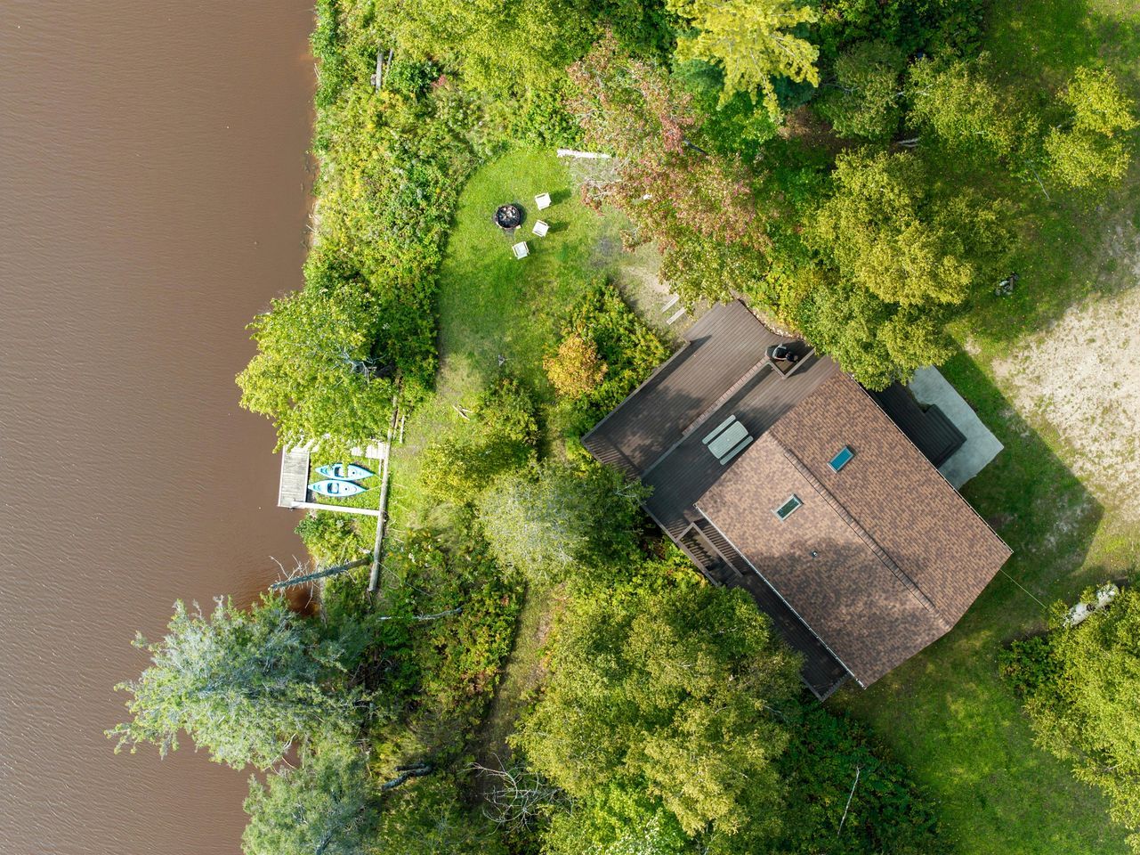 Vue aérienne d’une maison avec une cour clôturée, un quai et un bateau.