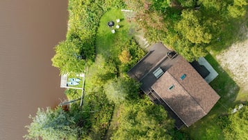 An aerial view of a house with a fenced yard, a dock, and a boat.