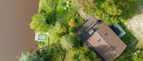 An aerial view of a house with a fenced yard, a dock, and a boat.