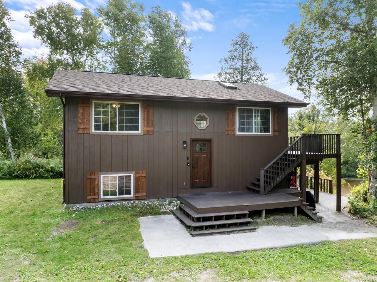 Eine zweistöckige Holzhütte mit Veranda, Treppe und einer Terrasse.