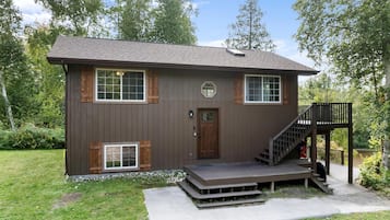 Eine zweistöckige Holzhütte mit Veranda, Treppe und einer Terrasse.