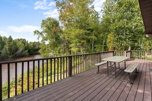 Una terraza con mesa y banco que da a un río, rodeada de árboles.