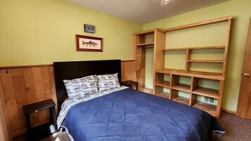 Une chambre à coucher avec un lit, une tête de lit en bois, un ventilateur de plafond et des étagères intégrées.