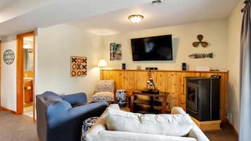 Ein Wohnzimmer mit Fernseher, Kamin, Sofa, Sessel und Lampe.