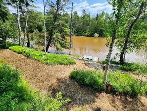 A natural landscape with a body of water, trees, and a wooden dock. - Riverfront Cabin Incredible for Outdoor Enthusiasts with Kayaks in Hessel, Michigan (Hessel)