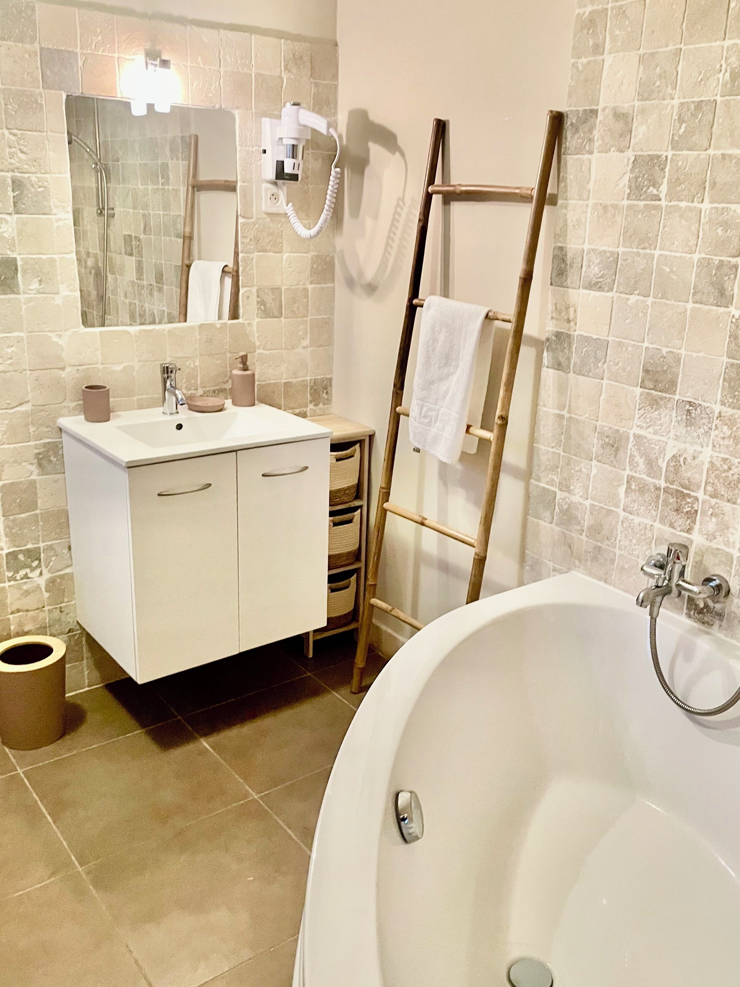 A bathroom with a bathtub, a vanity with a mirror, a towel rack, and a shower area.