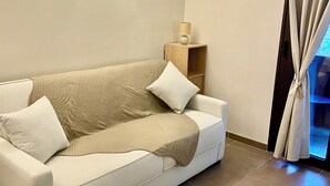 Ett modernt vardagsrum med en beige soffa, en lampa och en luftkonditioneringsanläggning på väggen.