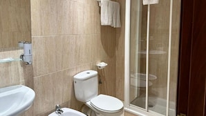 Et badeværelse med vask, toilet og brusekabine.
