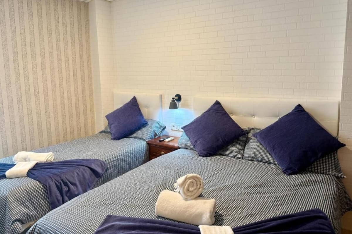 Una habitación de hotel con dos camas individuales, cada una con una almohada y una colcha.