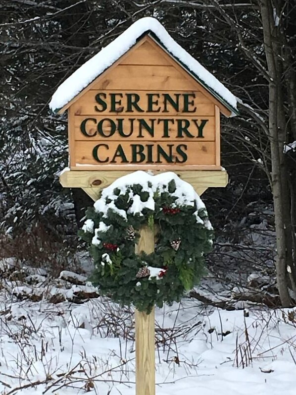 Un letrero de madera con el texto 'SERENE COUNTRY CABINS' y una guirnalda.