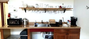 Una cocina equipada con microondas, tostadora, lavamanos y cafetera.