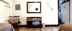 A room with a wooden chair, a framed star decoration, a whisk, and a door.