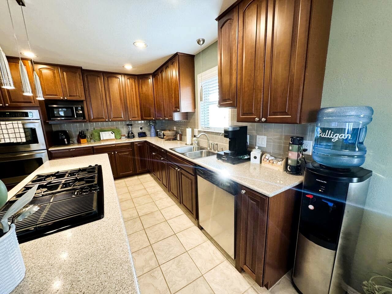 A modern kitchen with wooden cabinets, stainless steel appliances, and a water dispenser.