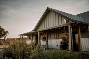 A building with a covered porch, a sloped roof, and a white fence. - Adventure-Ready A-Frame Cabins with Fire Pit & Cozy Mountain Setting in Emigrant, Montana (Emigrant)