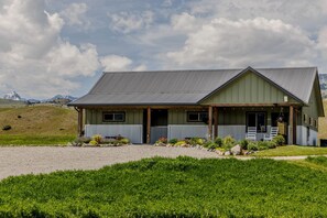 A two-story building with a covered porch and a gravel driveway. - Adventure-Ready A-Frame Cabins with Fire Pit & Cozy Mountain Setting in Emigrant, Montana (Emigrant)
