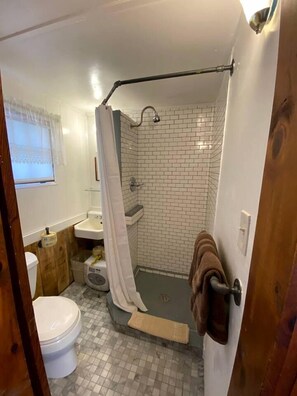 A small bathroom with a toilet, sink, and shower area. - Lakefront Cottage Rental near Bear Brook State Park in Northwood, New Hampshire (Northwood)