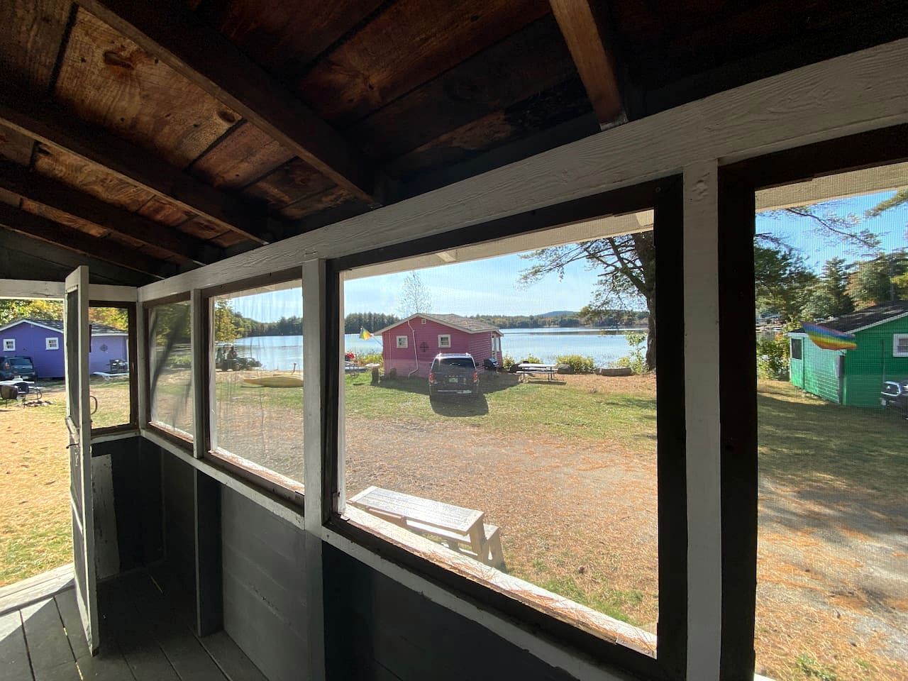 Quarto com vista para um lago, um edifício vermelho e um galpão verde.