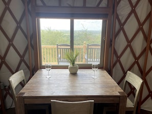 A wooden table with two chairs, a potted plant, and two wine glasses.