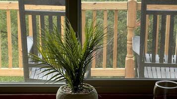 A balcony with a wooden railing, a potted plant, and a wine glass.