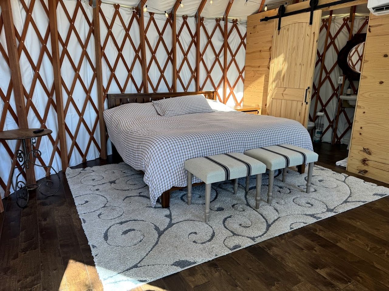 A bedroom with a bed, bench, and a patterned rug.