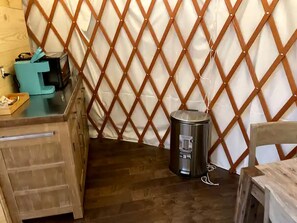 Una habitación con un escritorio de madera, un cubo de basura y una pared divisoria.