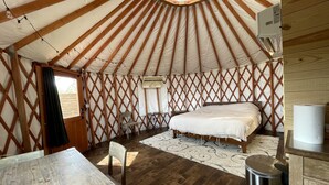 A yurt with a bed, a table, chairs, and a window.