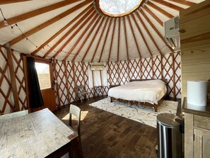 A yurt with a bed, a table, chairs, and a window.