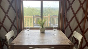 A wooden table with two chairs, a potted plant, and two wine glasses.