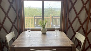 A wooden table with two chairs, a potted plant, and two wine glasses. - Texas Yurt for a Unique Glamping Holiday (Mineral Wells)