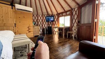 Ein Zimmer mit einem Bett, einem Holztisch, einem Fernseher und einem Fenster.