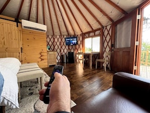 A room with a bed, a wooden table, a TV, and a window.