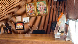 Eine Holzbodenverkleidung, gerahmte religiöse Gemälde, ein Google Pay QR-Code und eine kleine Kapelle mit Gänseblümchenblumen.