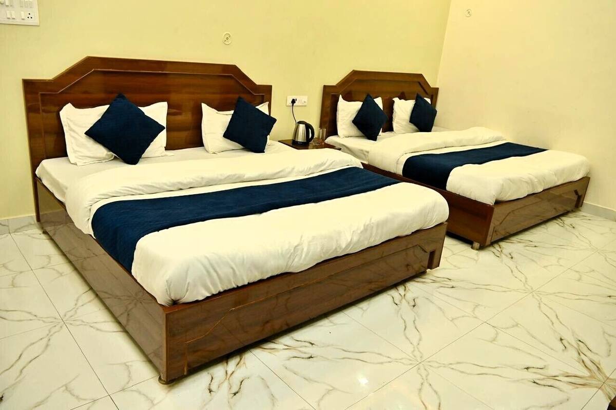 Habitación de hotel con dos camas, cada una con cabeceros de madera y ropa de cama blanca.