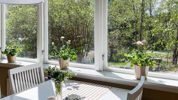 A room with a large window, a table with chairs, and potted plants.