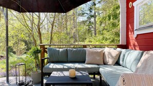 A covered outdoor seating area with a sofa, a table, and a lantern. - 4 Star Holiday Home in Vato (Vätö)