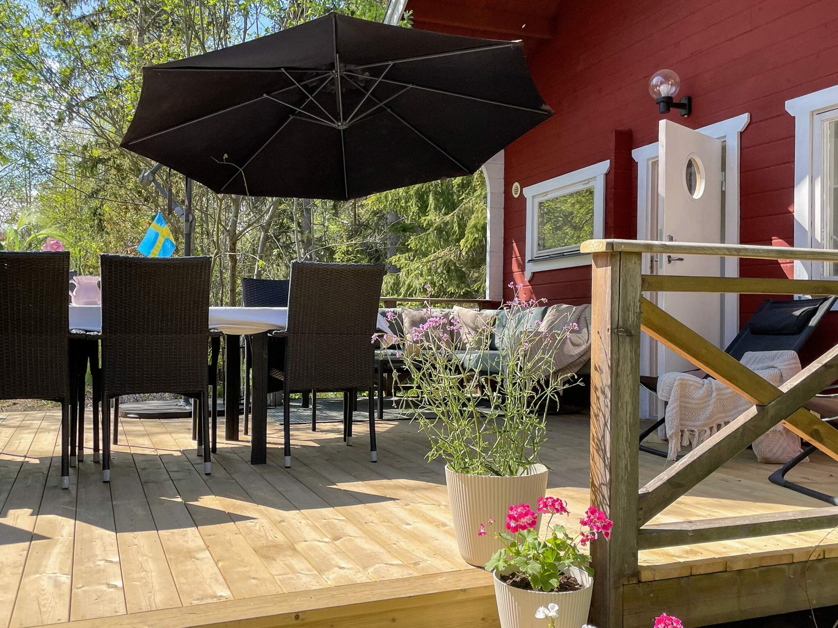 A wooden deck with outdoor furniture, including a table and chairs, and a large umbrella.