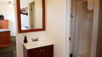 A bathroom with a wooden vanity, a mirror, and a shower area.