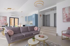 Ein modernes Wohnzimmer mit einem grauen Sofa, einem runden Couchtisch und einer Treppe, die zu einer anderen Ebene führt.