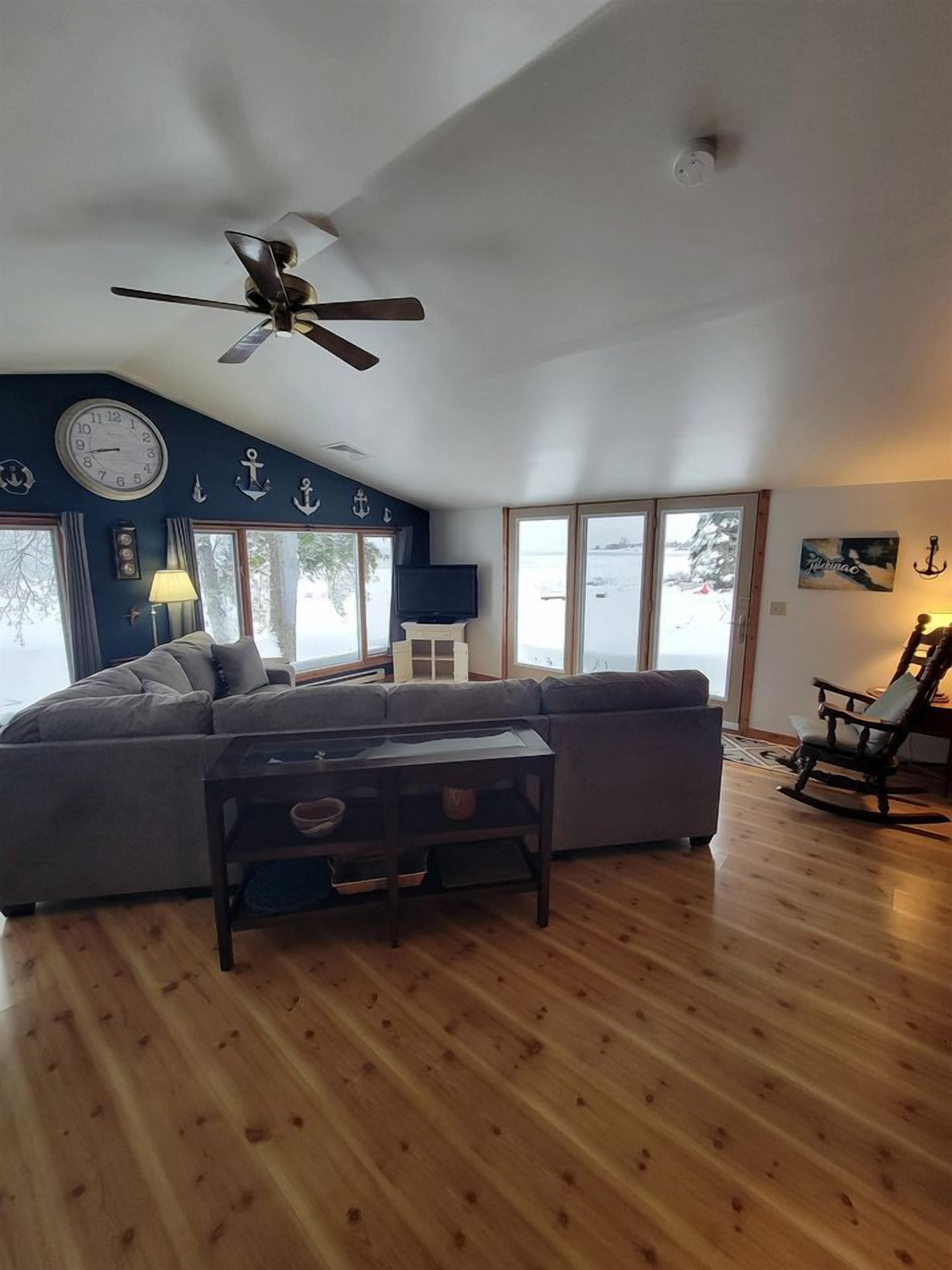A living room with a ceiling fan, a sofa, a coffee table, and a rocking chair.