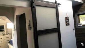 A room with a sliding barn-style door, a small window with a towel, and a sign that says 'LIVE LOVE LAKE.'