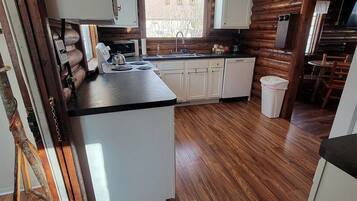 A kitchen with wooden flooring, white cabinets, and a central island.